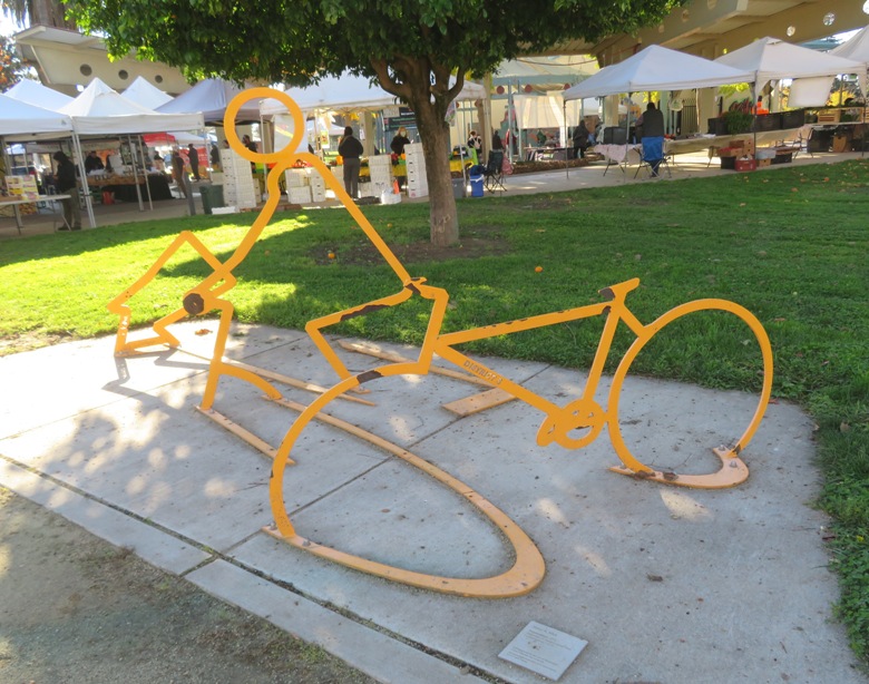 Yellow metal sculture of bicyclist falling