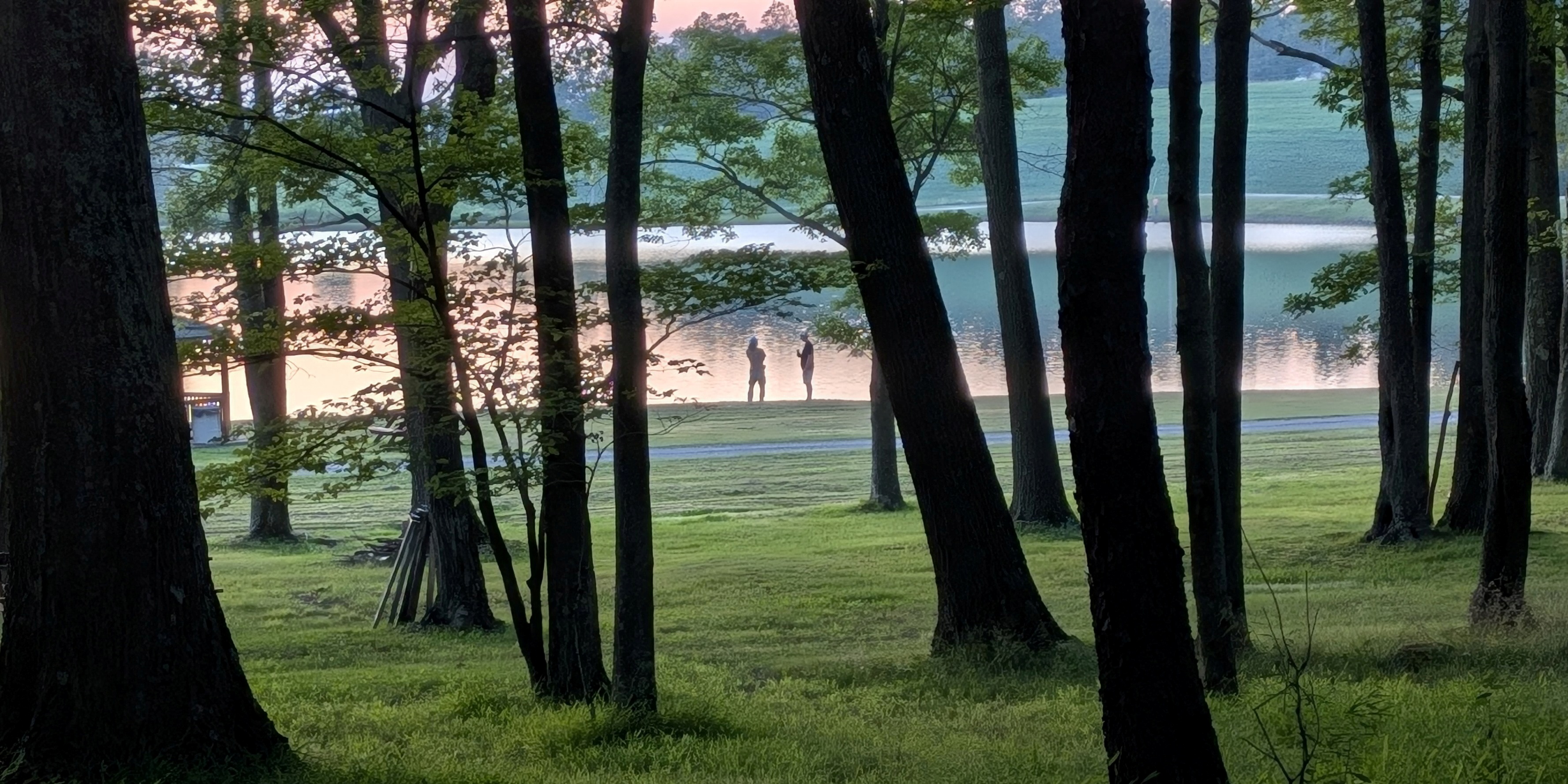View through the woods of Jimmy and me talking at the lake
