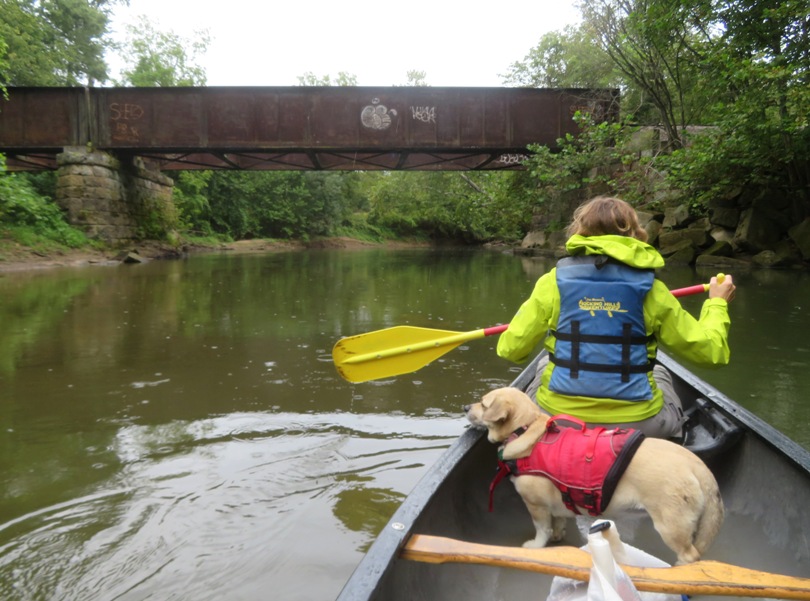 Norma and Daphne in canoe with old metal bridge ahead
