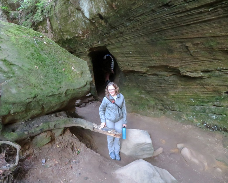 Norma standing with tunnel in cliff behind her