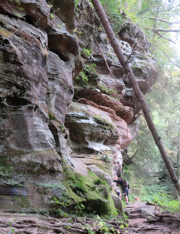 Hikers at the base of a vertical rock formation