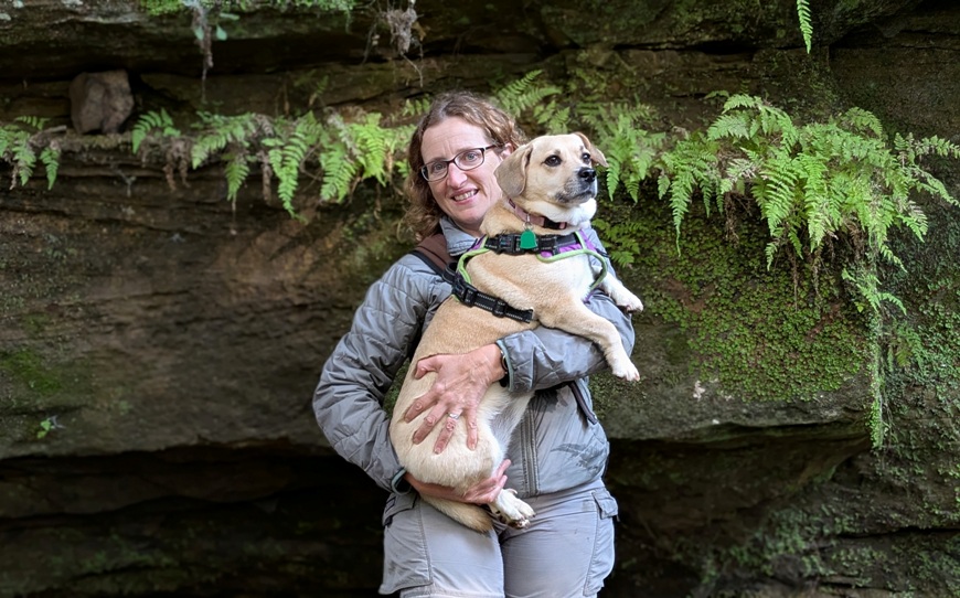 Close-up of Norma holding Daphne with rock wall behind