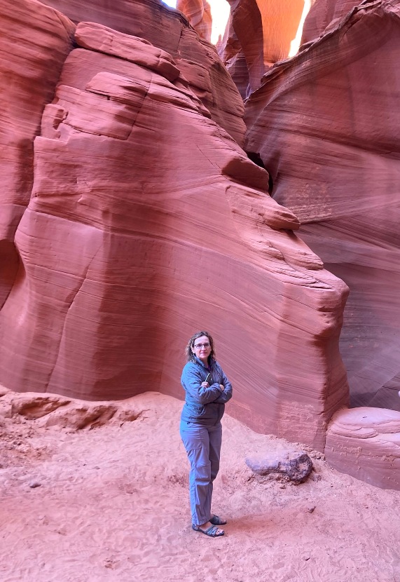 Norma standing with arms crossed in front of red rocks