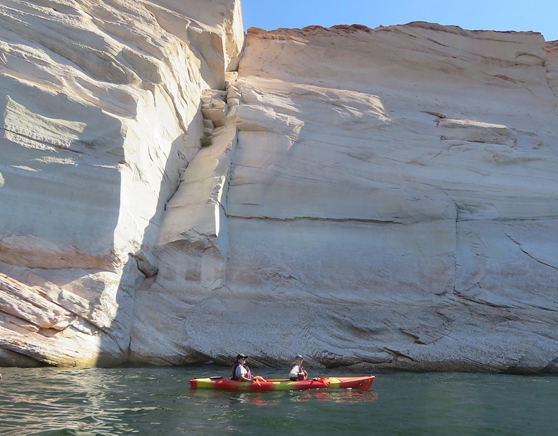 Robin and Carmen kayaking in the slot canyon with white stone wall behind
