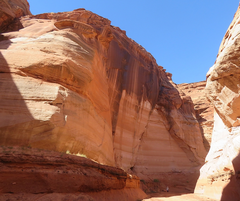 View of small hiker by a tall cliff wall