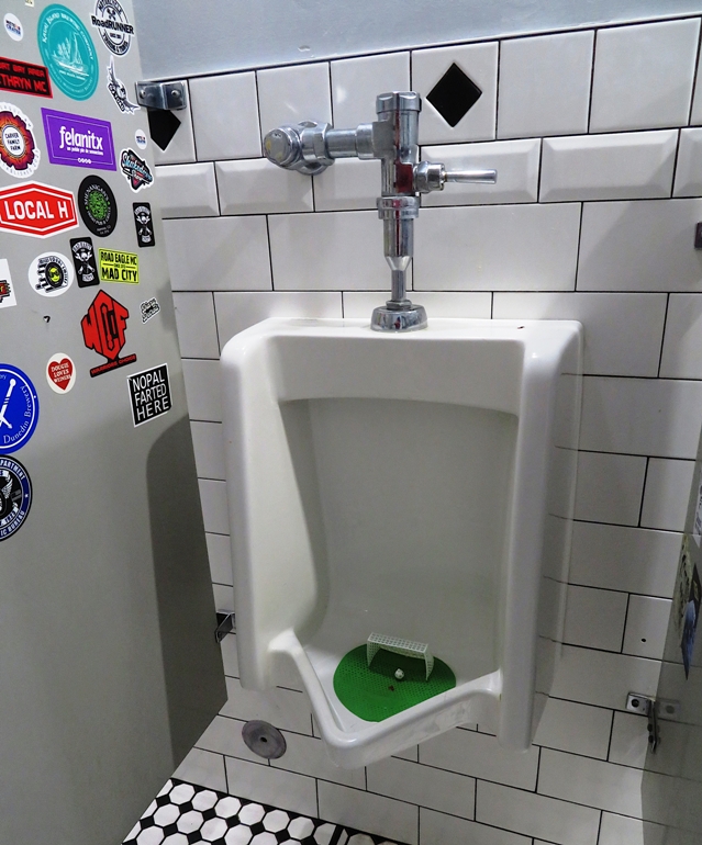 Urinal with miniature soccer goal and ball