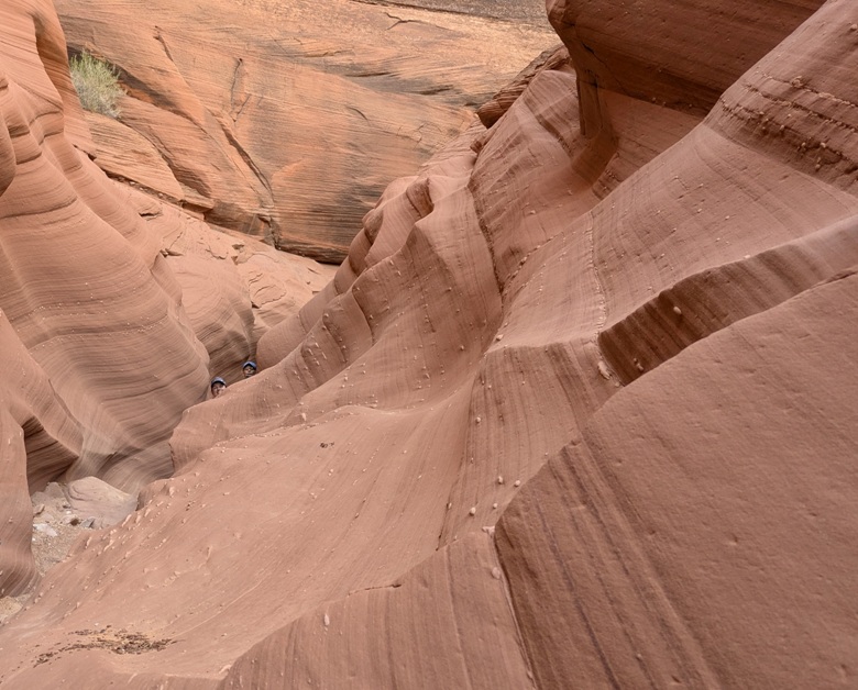 Robin and Carmen look over the top of a wavy wall in the canyon