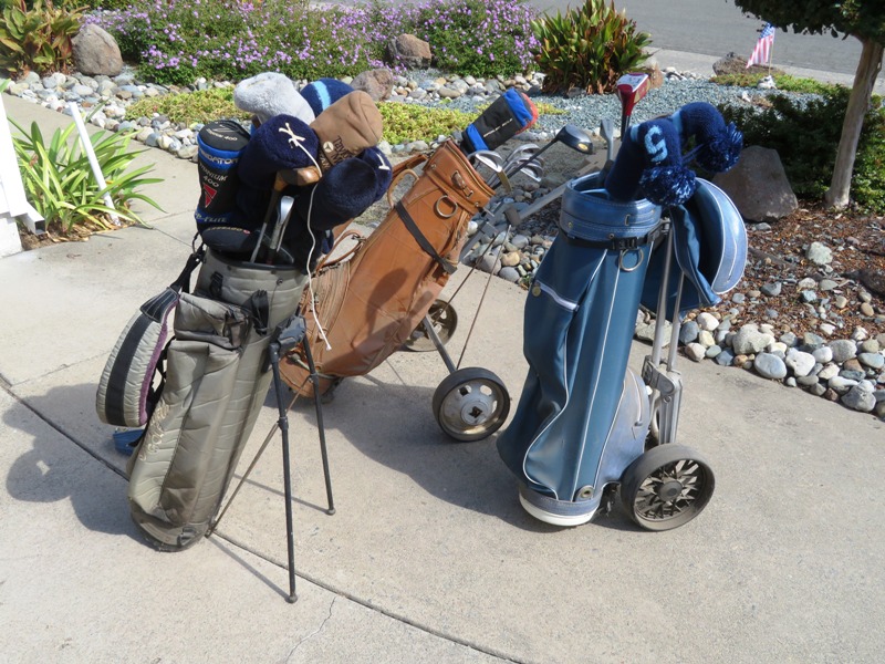 Three golf bags with clubs