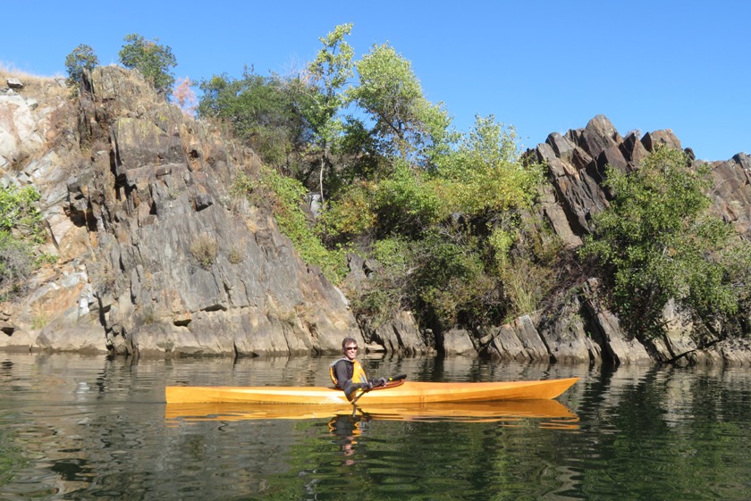 Ken in his kayak in front of dark boulders