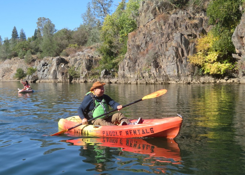 Steve paddling rental kayak with dark boulders behind