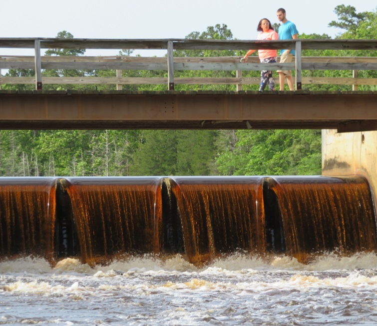 Brown water flowing over dam