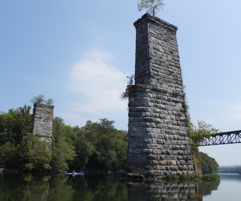 Jimmy kayaking by big, old stone bridge supports