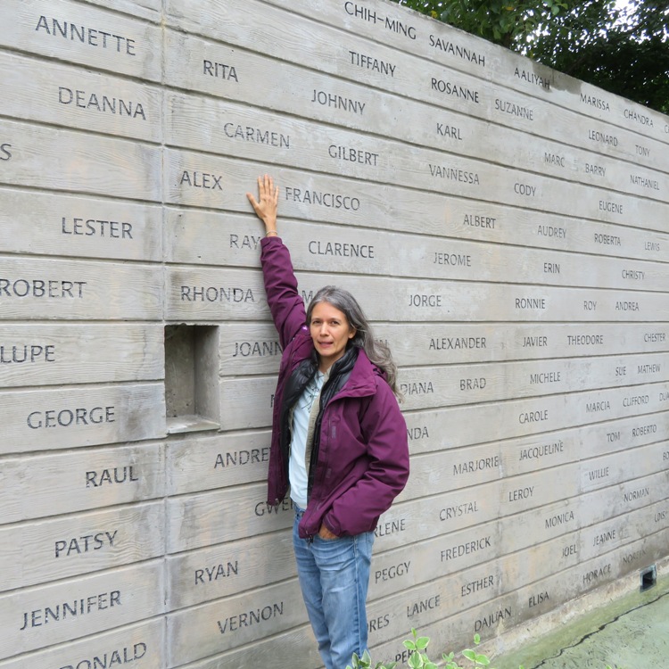 Carmen reaching up to her name on the Wall of Names