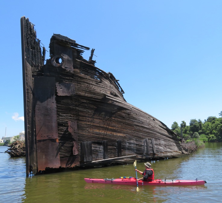 Steve kayaking by wooden shipwreck