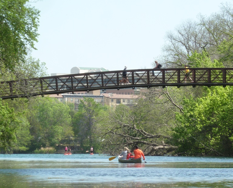 Family in canoe under pedestrian bridge