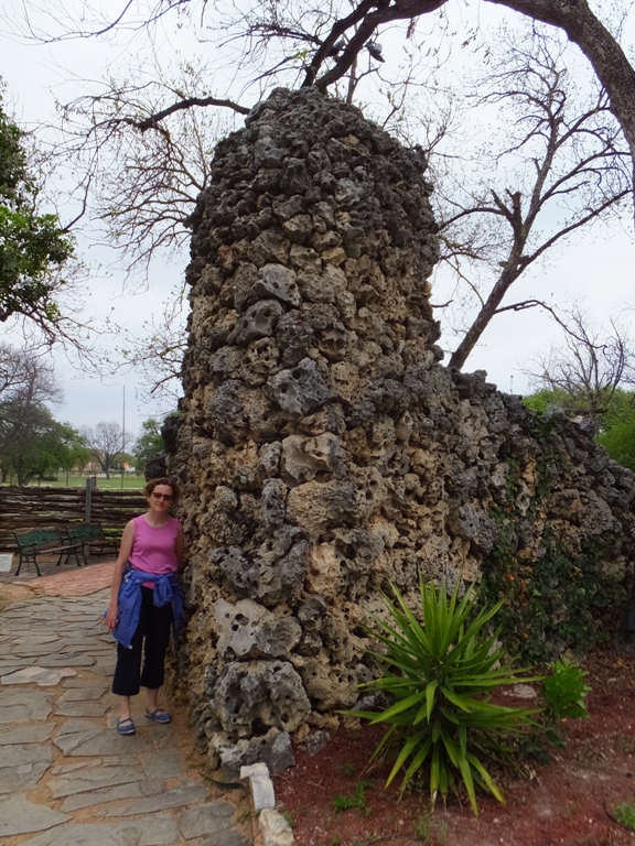 Norma standing next to a rock structure that looks like it is made of skulls