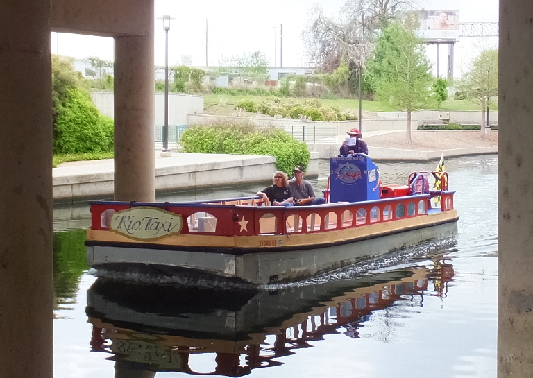 Water taxi passing under bridge with two passengers