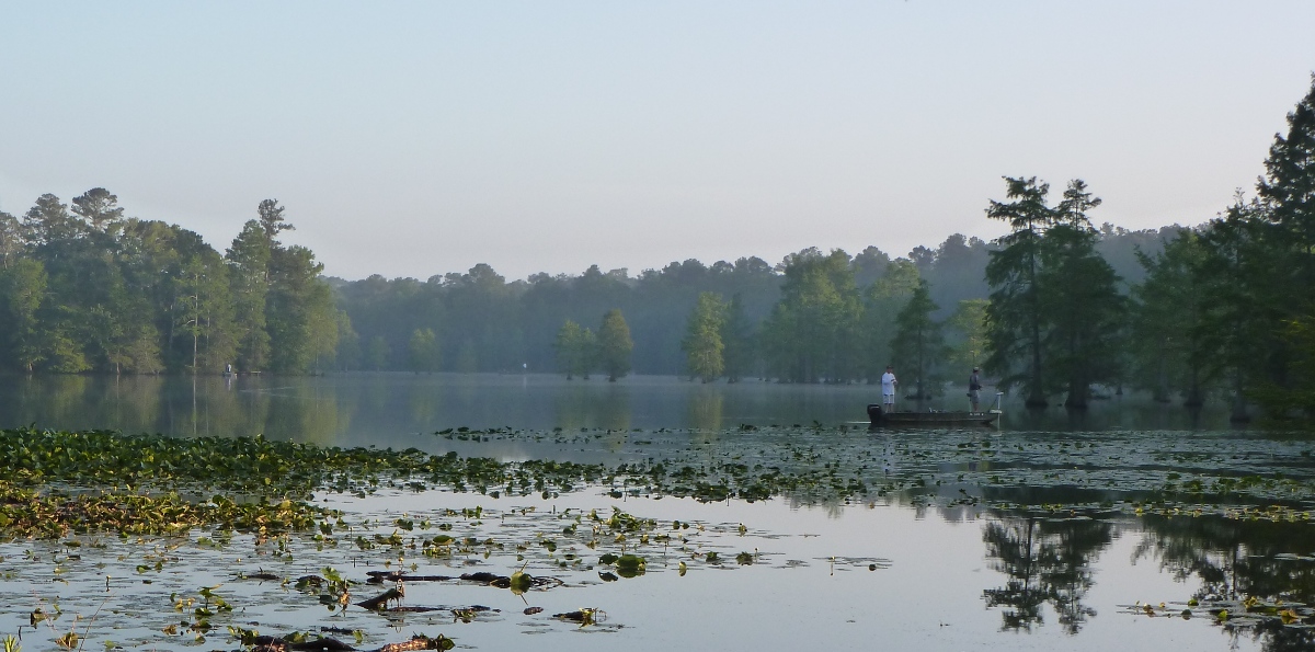 People on boat fishing on hazy pond