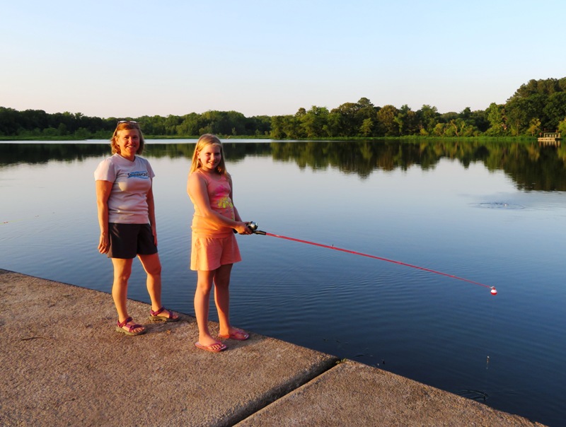 Stacy and her granddaughter with fishing pole in hand