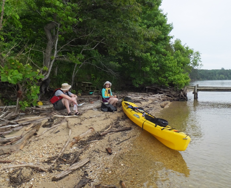 Chris and Norma on beach, eating lunch with tandem kayak closer to the water