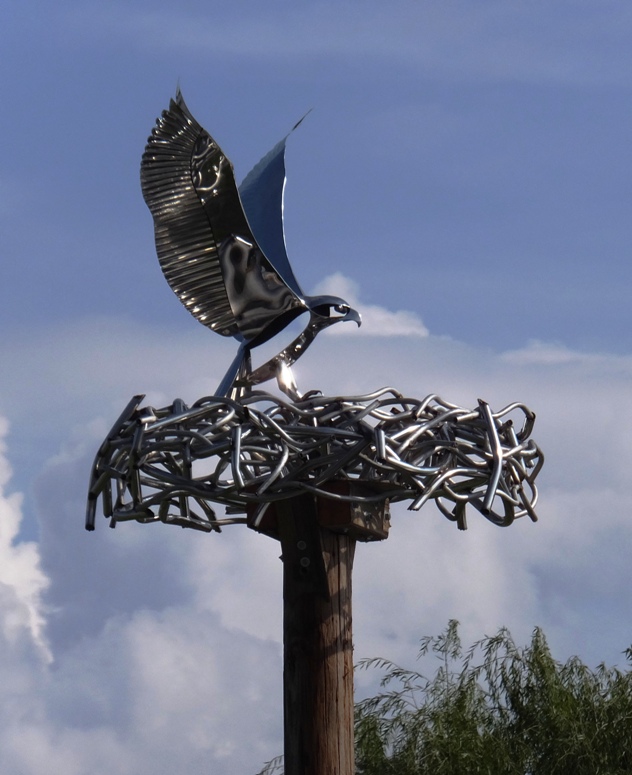 Metallic sculpture of raptor at its nest