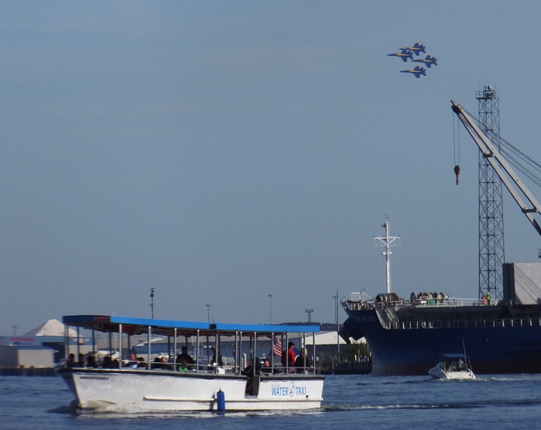 Four Blue Angel planes in the background with a water taxi in the foreground