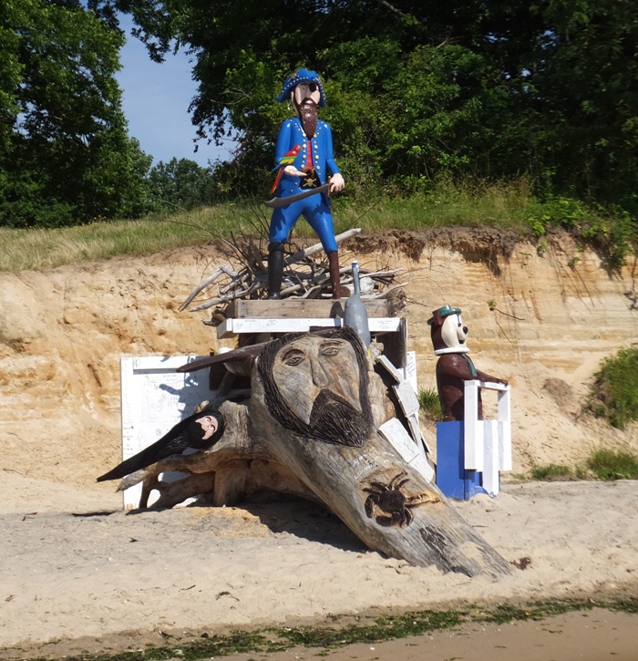 Sculpture of a pirate and Yogi Bear with a carving in a log of a crab and Jesus