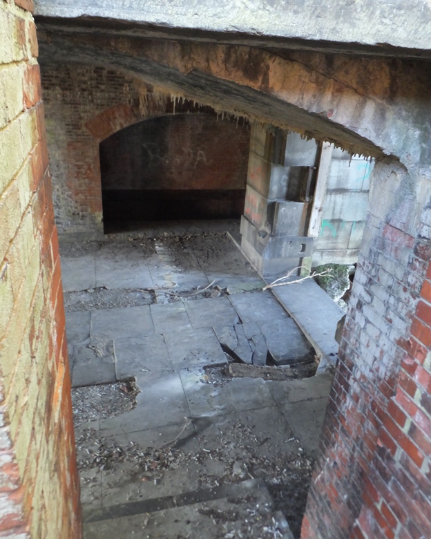 Broken stone floor and brick walls seen looking down from stairs