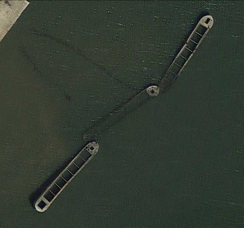 Satellite photo of three concrete barges and concrete pier