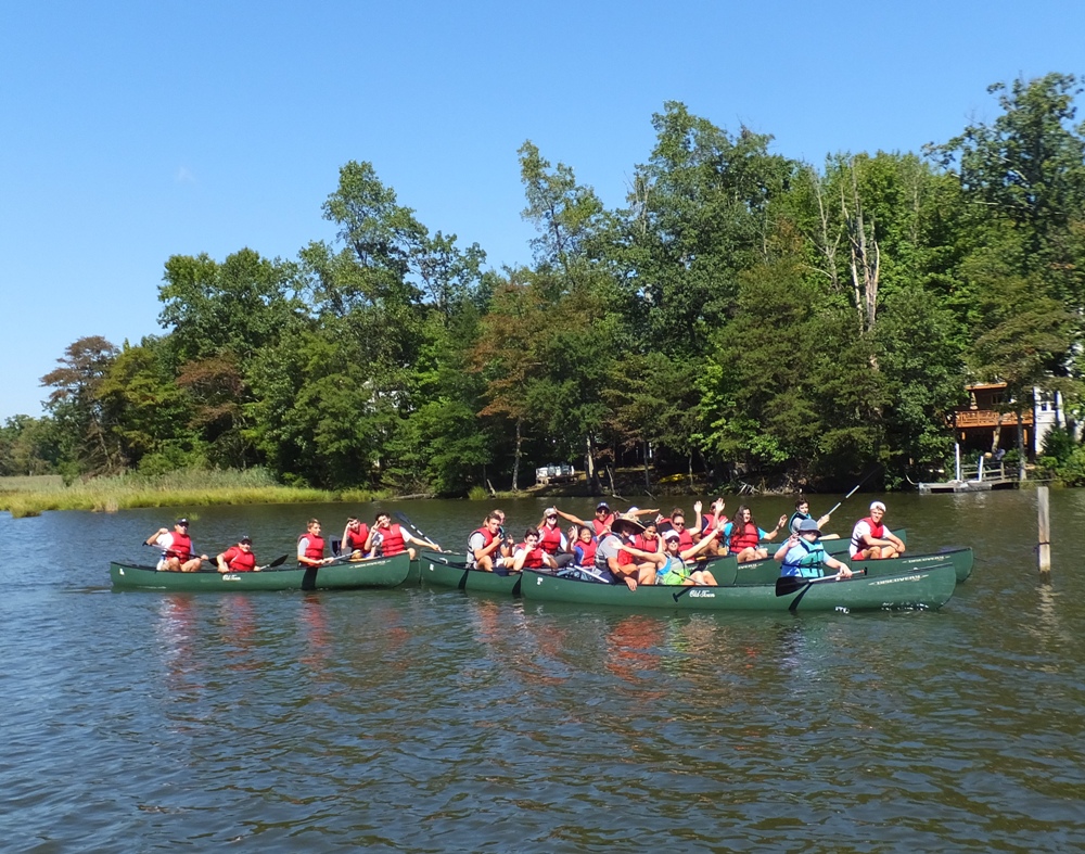 Group photo of at least seven canoes with paddlers