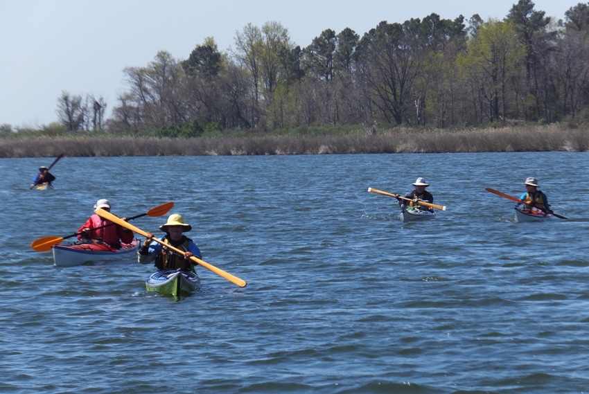 Five kayakers with their faces in the shadows of their hats
