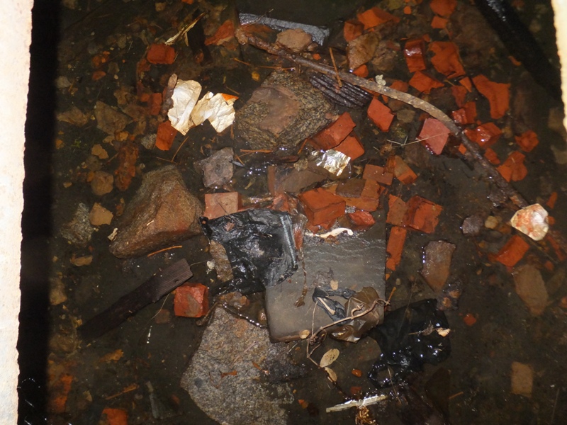 Looking inside the hole, there are a lot of bricks and some trash