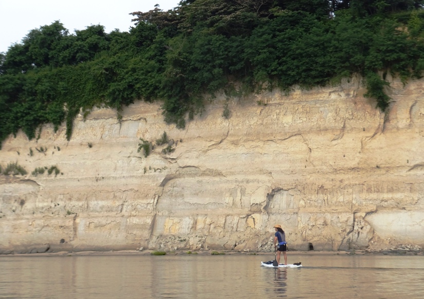 Me on SUP paddling towards steep cliff