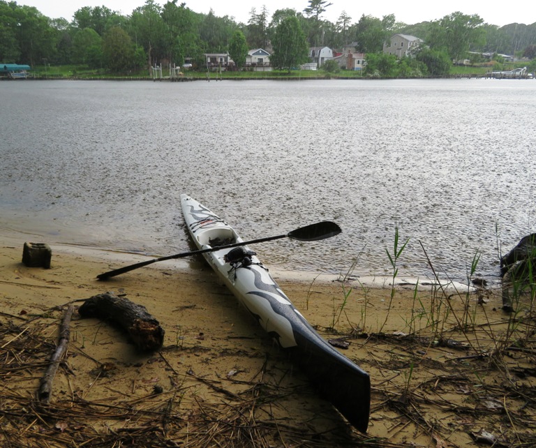 Surfski and paddle on beach with hard rain hitting water