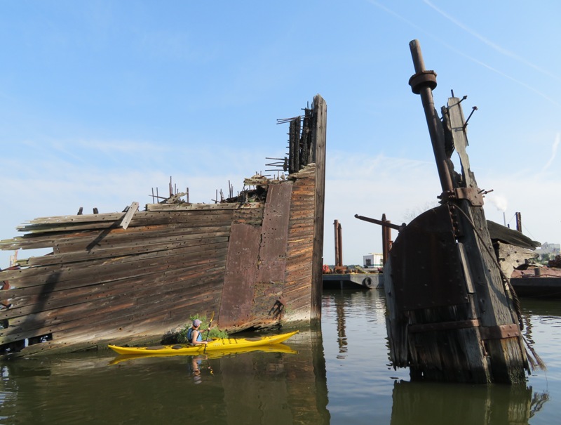 Sara kayaking by shipwreck with lots of metal rods sticking out