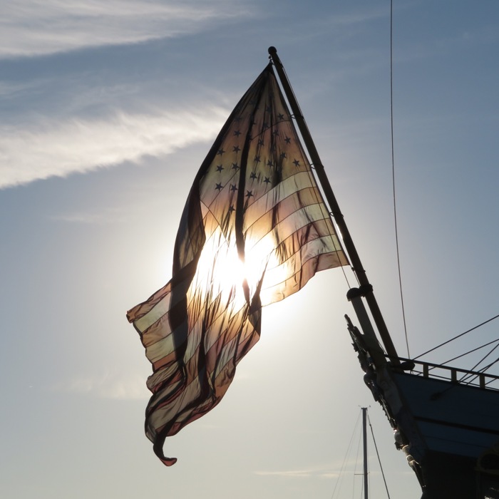 U.S. flag on the Kalmar Nyckel with sun behind