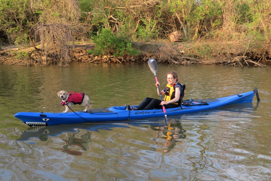 Daphne standing on the front of the kayak as Norma paddles