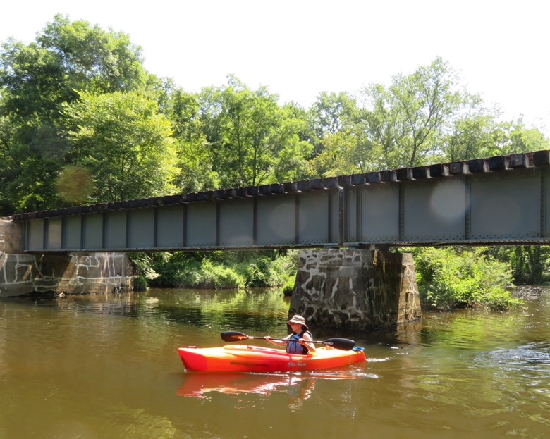 Sara kayaking under old railroad bridge