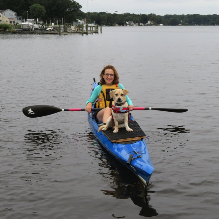 Norma smiling in her kayak with Daphne at the bow