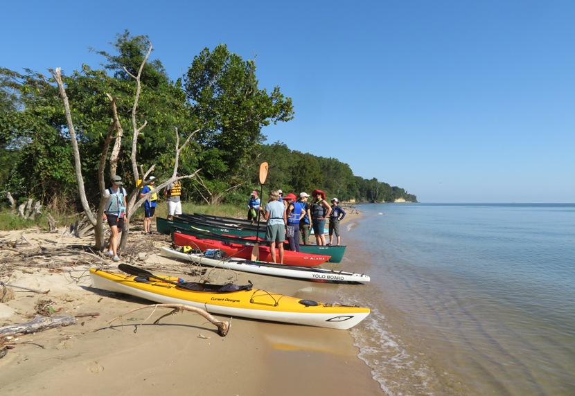 Boats staged on the beach with paddlers standing by