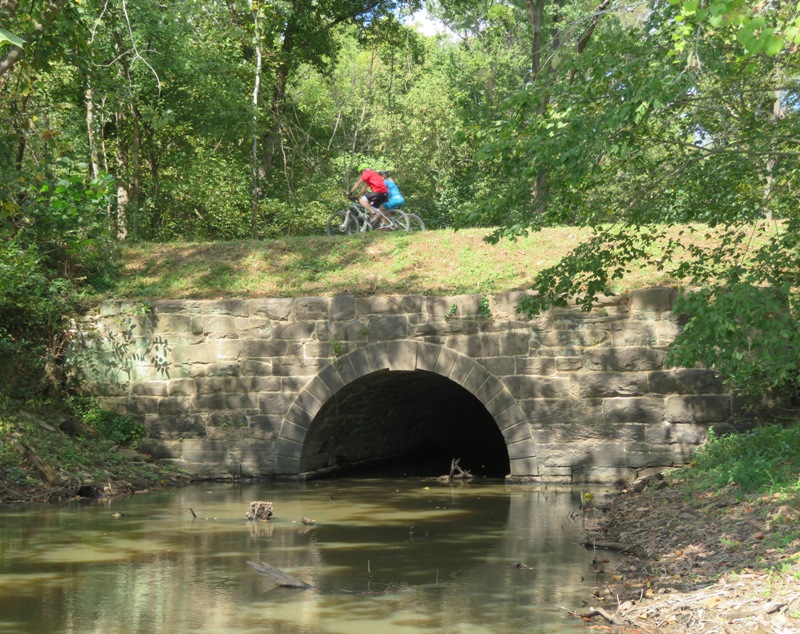 Couple of bicyclists on a stone bridge section of the towpath
