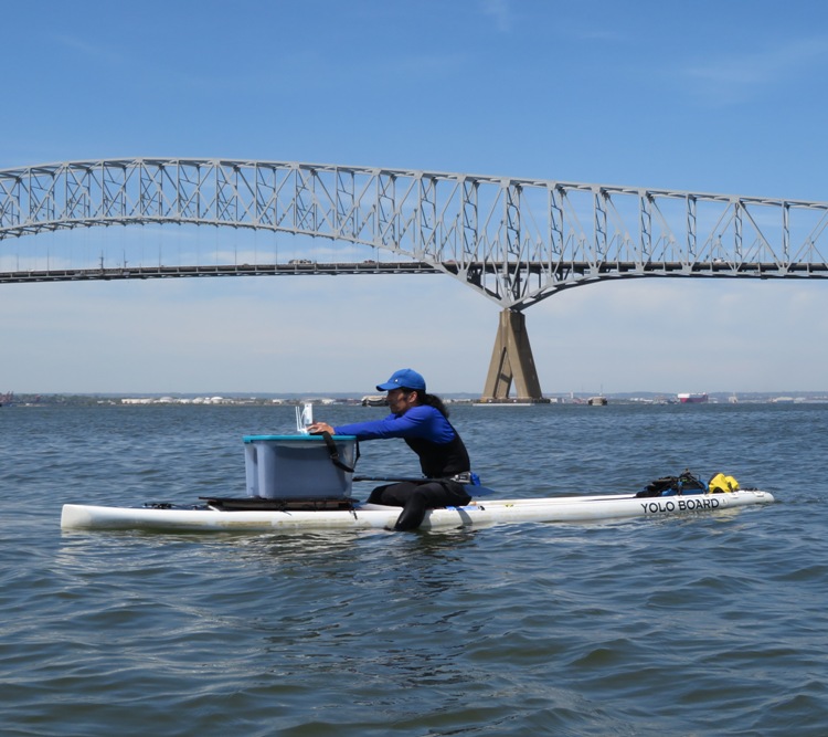 Me sitting on SUP piloting drone with Key Bridge in background