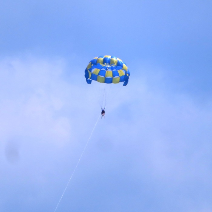 Someone parasailing with a blue and yellow chute