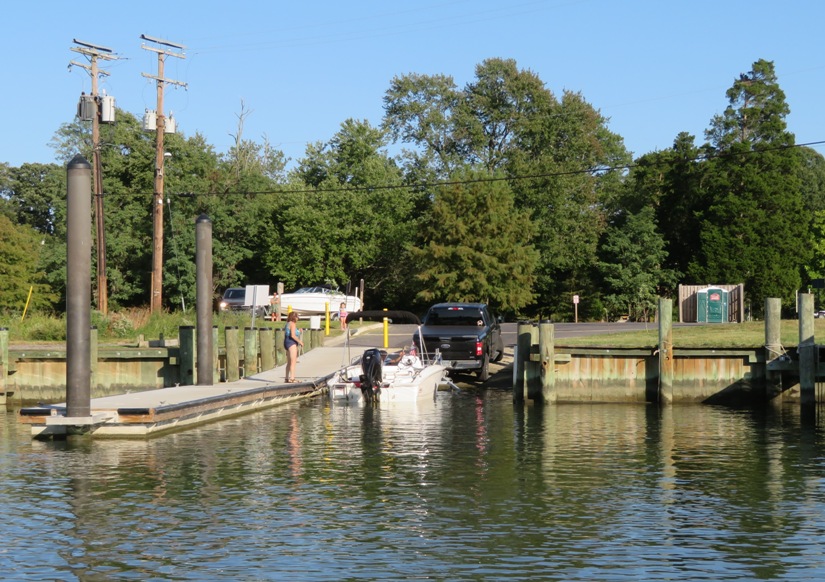 Boat ramp, power boat, trailer, vehicle, and person on pier