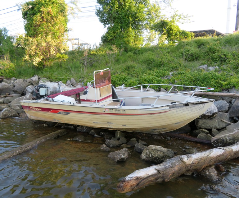 Modern power boat aground on rip rap