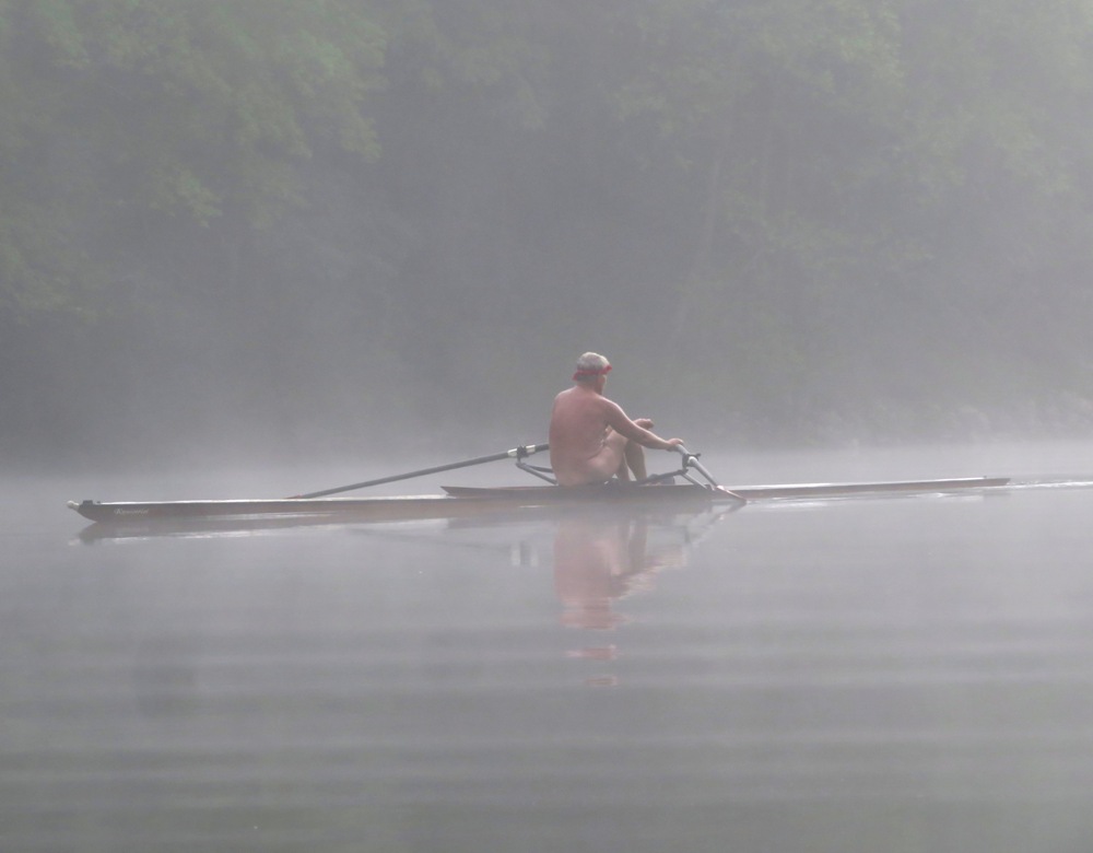 Back side of naked man rowing