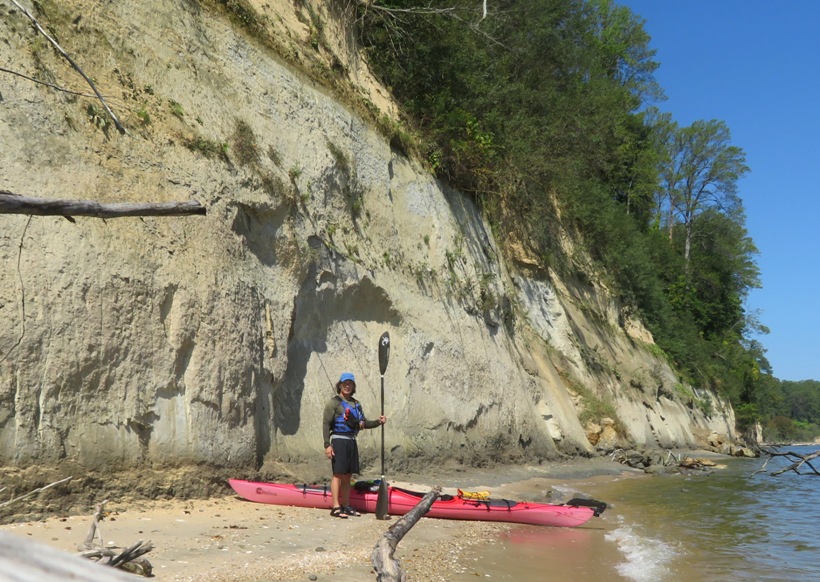 Me standing by my kayak in front of a beach cliff