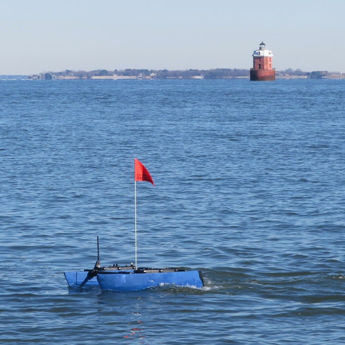 Blue drone catamaran with Sandy Point Shoal Lighthouse in the distance
