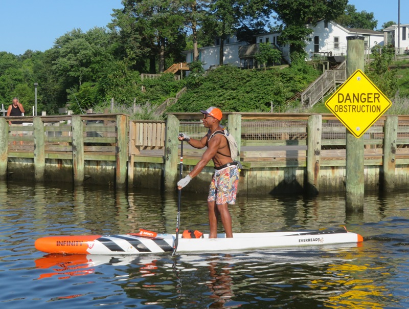 Ellison paddling by 'Danger Obstruction' sign