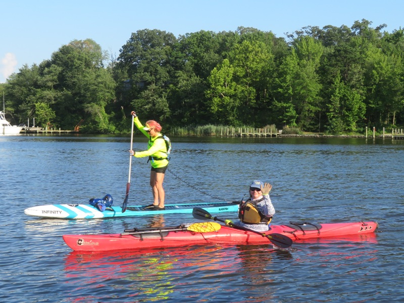 Lisa on kayak with paddleboarder behind